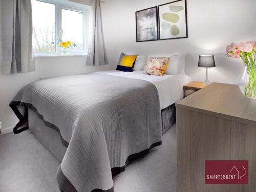 a bedroom with a bed with a blanket on it at Farnborough - Modern 2 Bedroom House in Blackwater