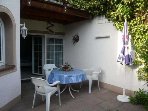 una mesa, sillas y una sombrilla en el patio en Villa Roder, en Umkirch
