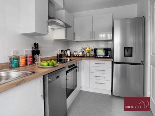 a kitchen with white cabinets and a stainless steel refrigerator at Bracknell - 2 Bedroom Home With Garden & Parking in Easthampstead