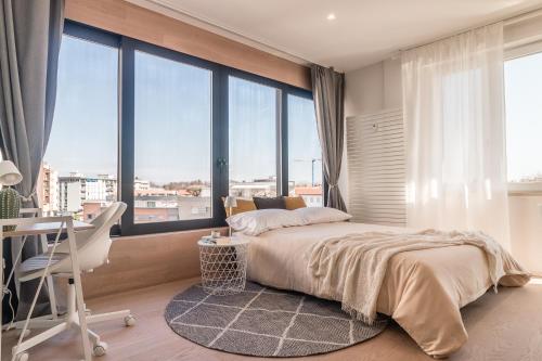 - une chambre avec un lit, un bureau et de grandes fenêtres dans l'établissement City Life Apartment Pordenone, à Pordenone