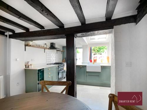 a kitchen with green cabinets and a table at Henley-On-Thames - 2 Bedroom Cottage With Permit Parking Close By in Henley on Thames