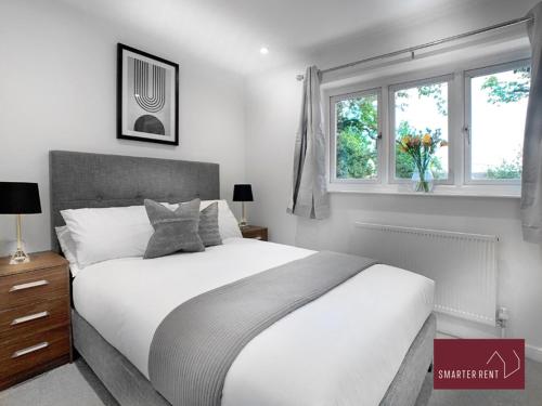 a bedroom with a white bed and two windows at West End, Woking - 2 Bed House With Parking and Garden in Bisley