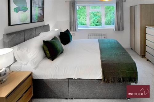 a bedroom with a large white bed with green pillows at Farnborough - Lovely 1 Bedroom House in Blackwater