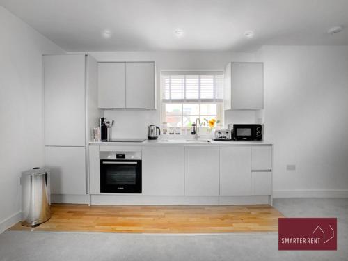 a white kitchen with white cabinets and a window at Eton, Windsor - 1 Bedroom First Floor Apartment - Parking in Eton