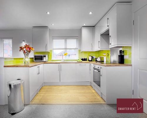 una cocina con armarios blancos y un jarrón de flores en Lovely Apartment, Maidenhead en Maidenhead