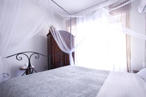 a white bedroom with a bed with a window at Porta Amari in Palermo