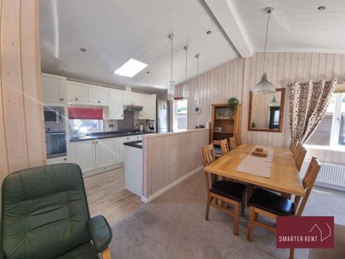 a kitchen with a wooden table and a dining room at Milford on Sea - 4 Bedroom Lodge in Shorefield Country Park in Milford on Sea
