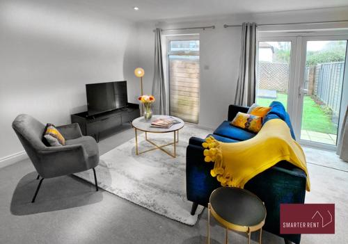 2 Bed House with Garden, Woking في Chobham: غرفة معيشة مع أريكة زرقاء وبطانية صفراء