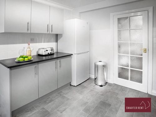 uma cozinha com armários brancos e uma bancada em Maidenhead - Lovely Modern 3 bedroom house em Maidenhead