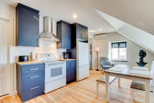 a kitchen with blue cabinets and a table with a laptop at Maison Grenier - Le Nid in Quebec City