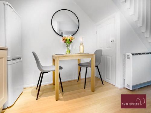 a dining room table with two chairs and a mirror at Bracknell - Modern, Spacious 1 Bedroom House in Easthampstead