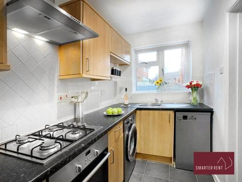 Il comprend une cuisine équipée d'une cuisinière et d'un évier. dans l'établissement Yateley - Spacious 2 Bedroom House, à Finchampstead