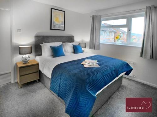 - une chambre avec un lit doté de draps bleus et une fenêtre dans l'établissement Yateley - Spacious 2 Bedroom House, à Finchampstead