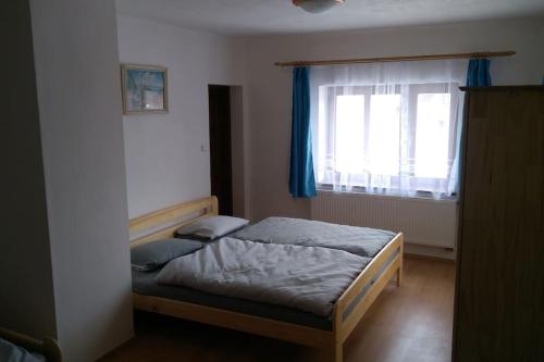 a bedroom with a bed and a window with blue curtains at Chalupa na Vysočině in Sněžné