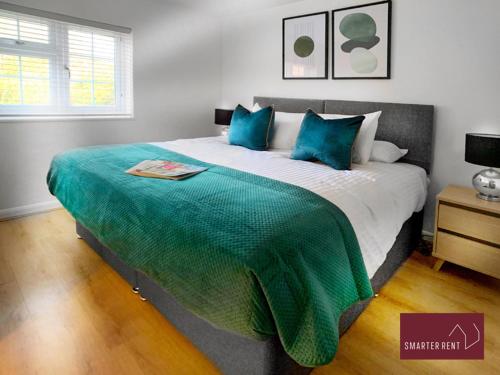 a bedroom with a large bed with blue pillows at Wokingham - 2 Bed Modern House - Parking in Wokingham
