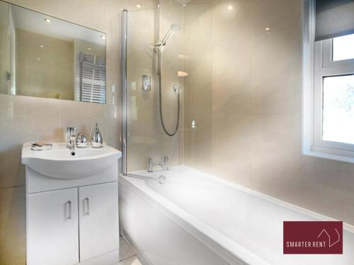 een badkamer met een bad, een wastafel en een douche bij Knaphill - 2 Bedroom House - With Parking in Brookwood