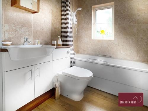 La salle de bains est pourvue de toilettes blanches, d'un lavabo et d'une baignoire. dans l'établissement Wokingham - 2 Bedroom House, à Wokingham