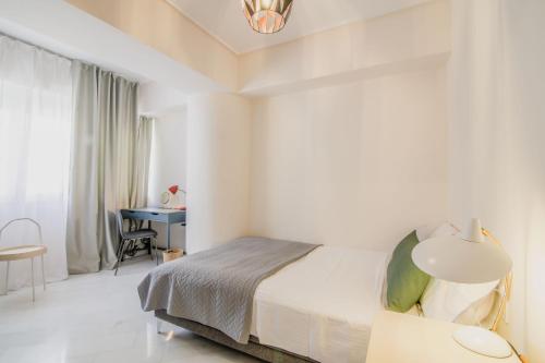 a white bedroom with a bed and a desk at The Urban Utopia at Glyfada in Athens