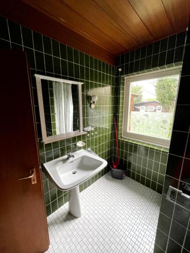 a green tiled bathroom with a sink and a window at 3-Z Monteurunterkunft in Einfeld in Neumünster