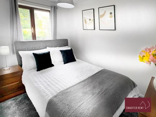 a bedroom with a bed with white sheets and blue pillows at Hitchin - Millstream - 2 Bedroom Coach House in Ickleford