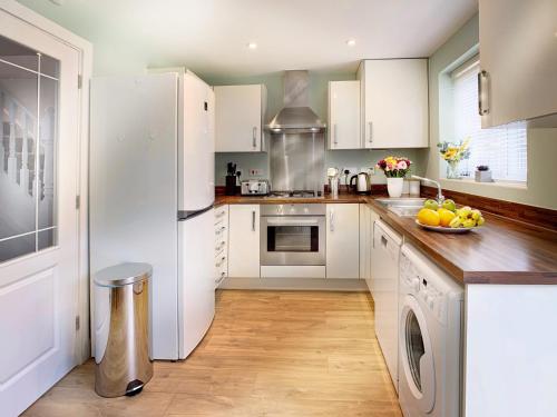 cocina con armarios blancos y nevera blanca en Wokingham - 2 bed House with garden, en Wokingham