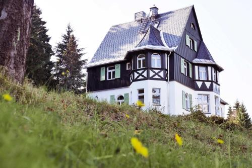 uma casa a preto e branco no topo de uma colina em Ahornallee em Kurort Bärenburg