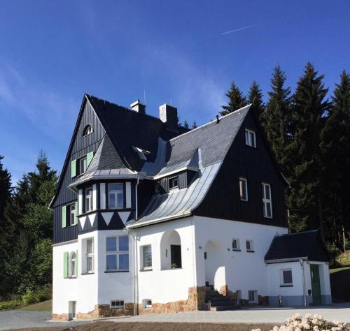 uma grande casa branca com um telhado preto em Ahornallee em Kurort Bärenburg