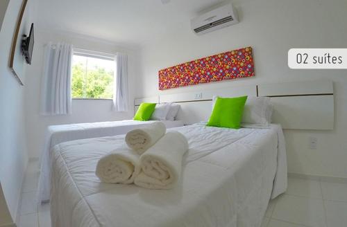 2 camas blancas en una habitación blanca con detalles verdes en Residencial Mont Carmelo - Tonziro, en Porto Seguro