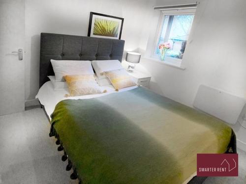 a bedroom with a large bed with a green blanket at Hitchin - Sharps Court in Hitchin