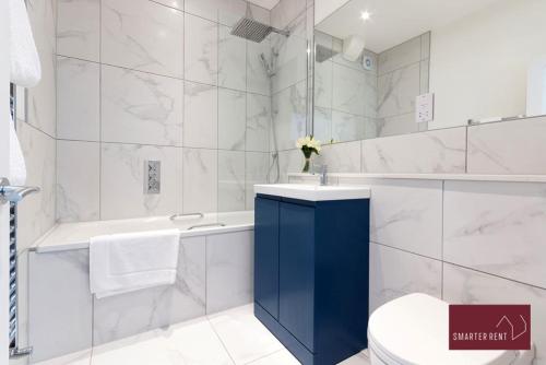 a bathroom with a toilet and a tub and a sink at Dorking - Brand New 1 Bedroom Apartment in Dorking