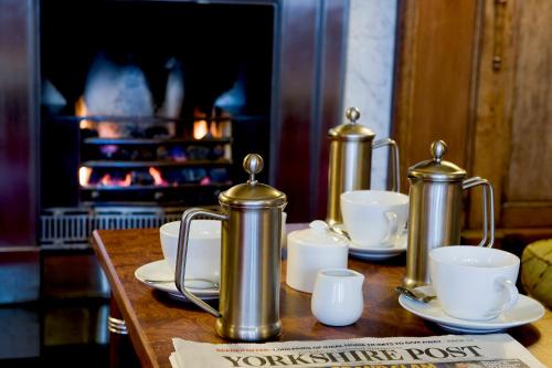 a table with silver tea pots and cups and a fireplace at Quebecs in Leeds