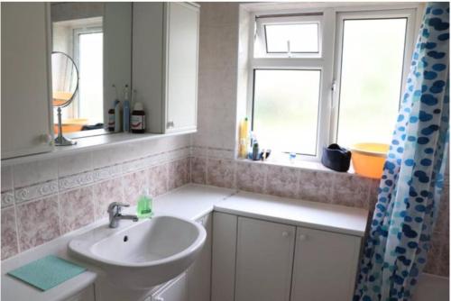 a bathroom with a sink and two windows at Wellesley, Central London Living in peaceful Suburb in Kenley