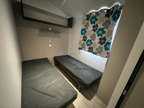 Cette petite chambre comprend un lit et un rideau. dans l'établissement Mobil home 6 personnes, à Saint-Cyprien