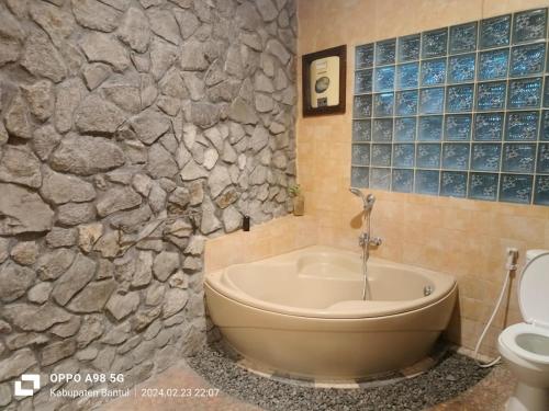 a bathroom with a bath tub and a toilet at Edhost D'Castillo in Tjepit