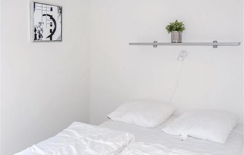 a bed with white sheets and a shelf on the wall at Awesome Home In Haderslev With 4 Bedrooms, Sauna And Indoor Swimming Pool in Kelstrup