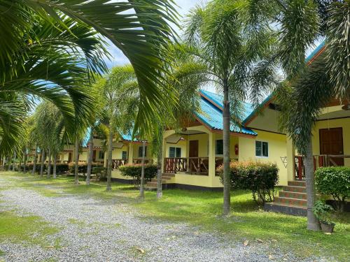 a row of palm trees in front of a house at Baanrimklong bungalow in Ko Chang