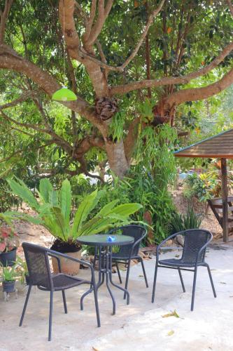 a table and chairs in front of a tree at Baanrimklong bungalow in Ko Chang