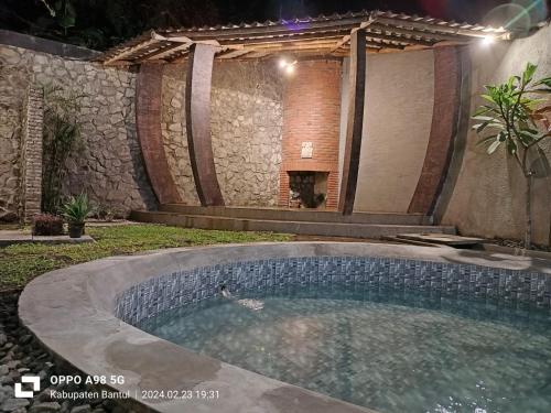 a swimming pool in a yard with a stone wall at Edhost D'Castillo in Tjepit
