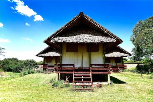 a small hut with a thatched roof on a field at The Lookout in Naivasha