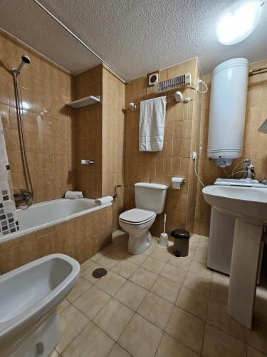 y baño con bañera, aseo y lavamanos. en Agradable apartamento familiar, en Sierra Nevada