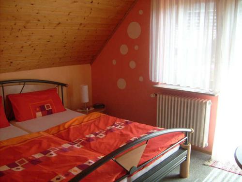 a bedroom with a bed with a red comforter at Gästehaus Birgitte in Ettenheim