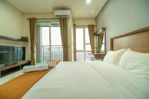 1 dormitorio con 1 cama blanca grande y TV en Charming & lovely 1BR Near GI Mall Thamrin, SCBD, en Yakarta