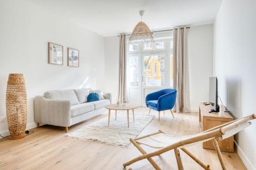Una sala de estar con un sofá y una silla azul. en Appartement Aigrette - La Maison Heureuse - Welkeys, en Saint-Georges-dʼOléron