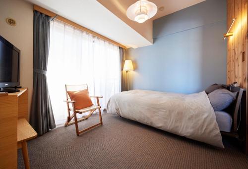 a hotel room with a bed and a chair and a television at Shibuya apartment SHINSEN in Tokyo