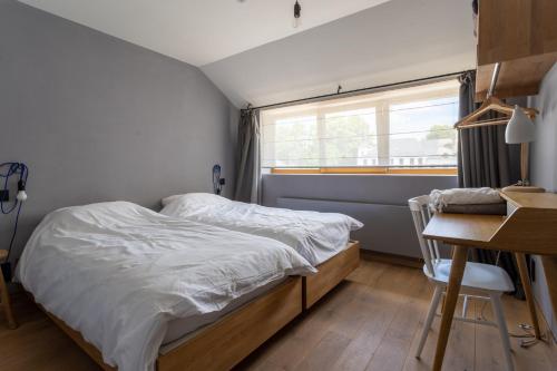a bedroom with a bed and a desk and a window at Domaine St Roch in Couvin