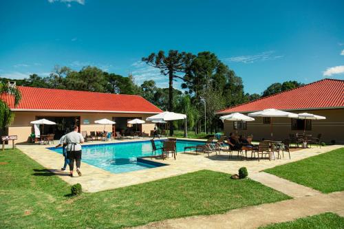 un homme marche au bord d'une piscine dans l'établissement Hotel Nativa Eco, à Mandirituba