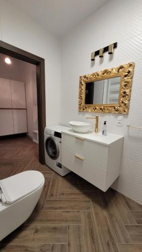 a bathroom with a sink and a toilet and a mirror at APARTAMENT JARACZA 28/9 in Słupsk