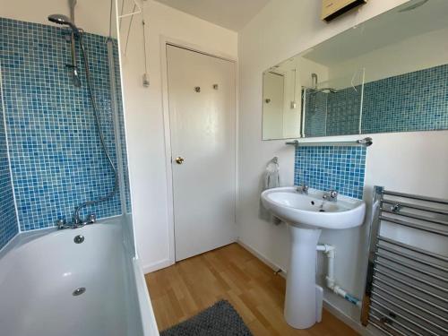 a bathroom with a sink and a toilet and a tub and a mirror at 2 Bed House in Hampton - Free parking in Hanworth
