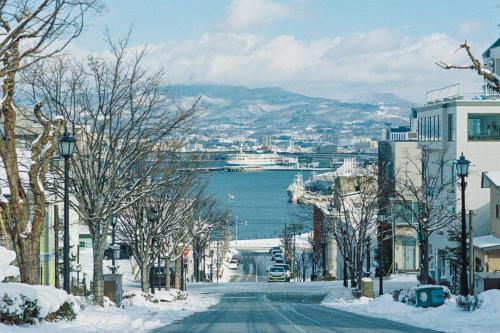 a snowy street in a city with a harbor at Portside Inn Hakodate in Hakodate