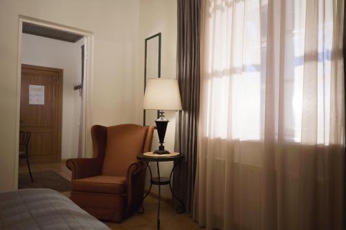 a room with a chair and a lamp and a window at Karlamuiza Country Hotel in Kārļi